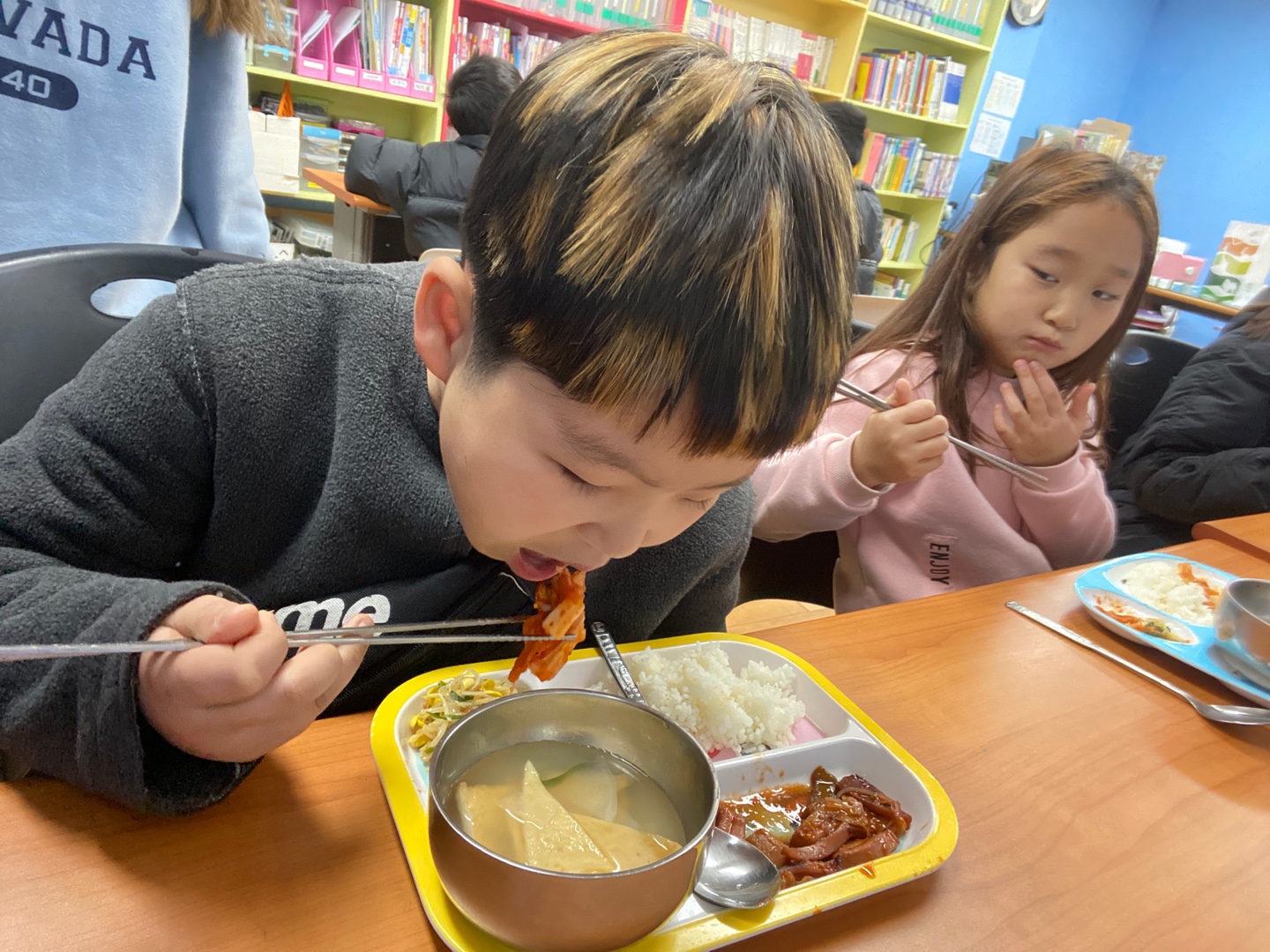 신승우 학생이 새로운 김치가 맛있다며 먹는 모습입니다.